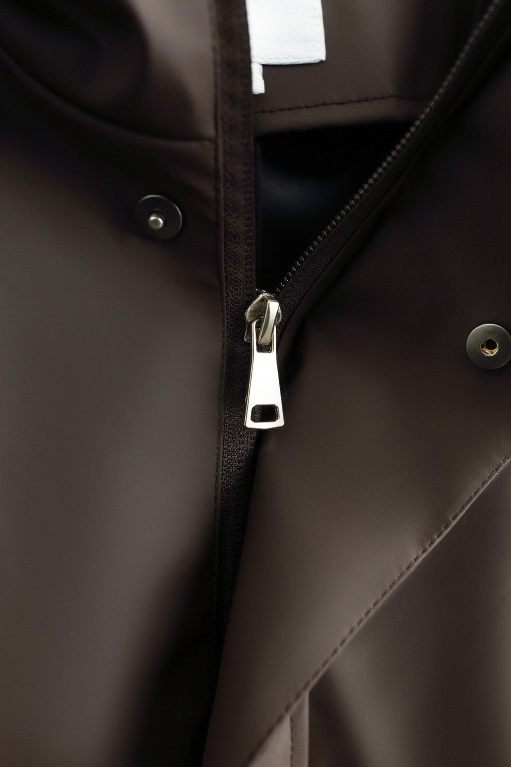 Détail de la fermeture du coupe-vent marron : zip et boutons-pression